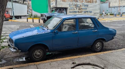 A royal blue four-door Renault of a model from the 1960s, perhaps? It has a long hood and a very short trunk.