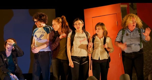 six actors, adults and young people, onstage looking confused or dismayed