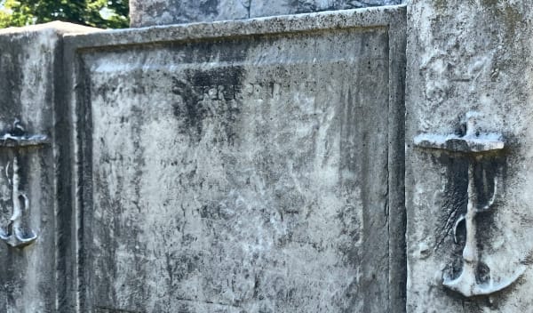 a detail of a burial monument, with anchors on either side of an illegible space where words were once engraved.
