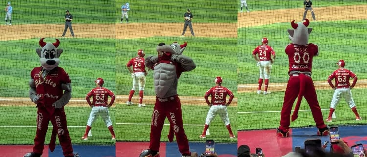 The mascot of the Diablos Rojos, a wolf with devil horns in a red uniform, glares on top of the dugout and then raises his jersey