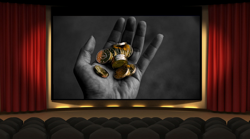 A black-and-white image of a hand holding several coins, displayed on a movie theater screen with red curtains and empty seats in the foreground.