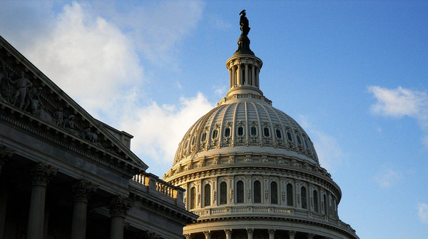 The dome of the United States Capitol building with a statue on top, set against a blue sky with scattered clouds.