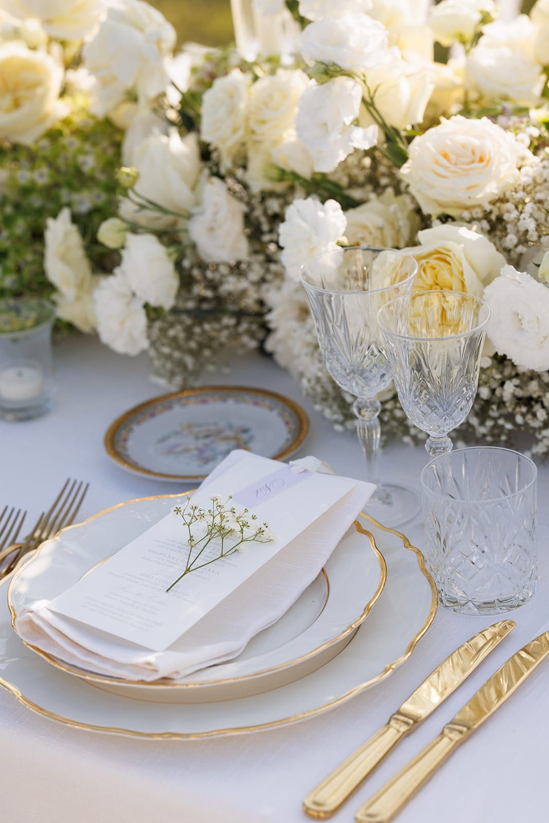 Gold-rimmed place setting with white florals and a folded napkin