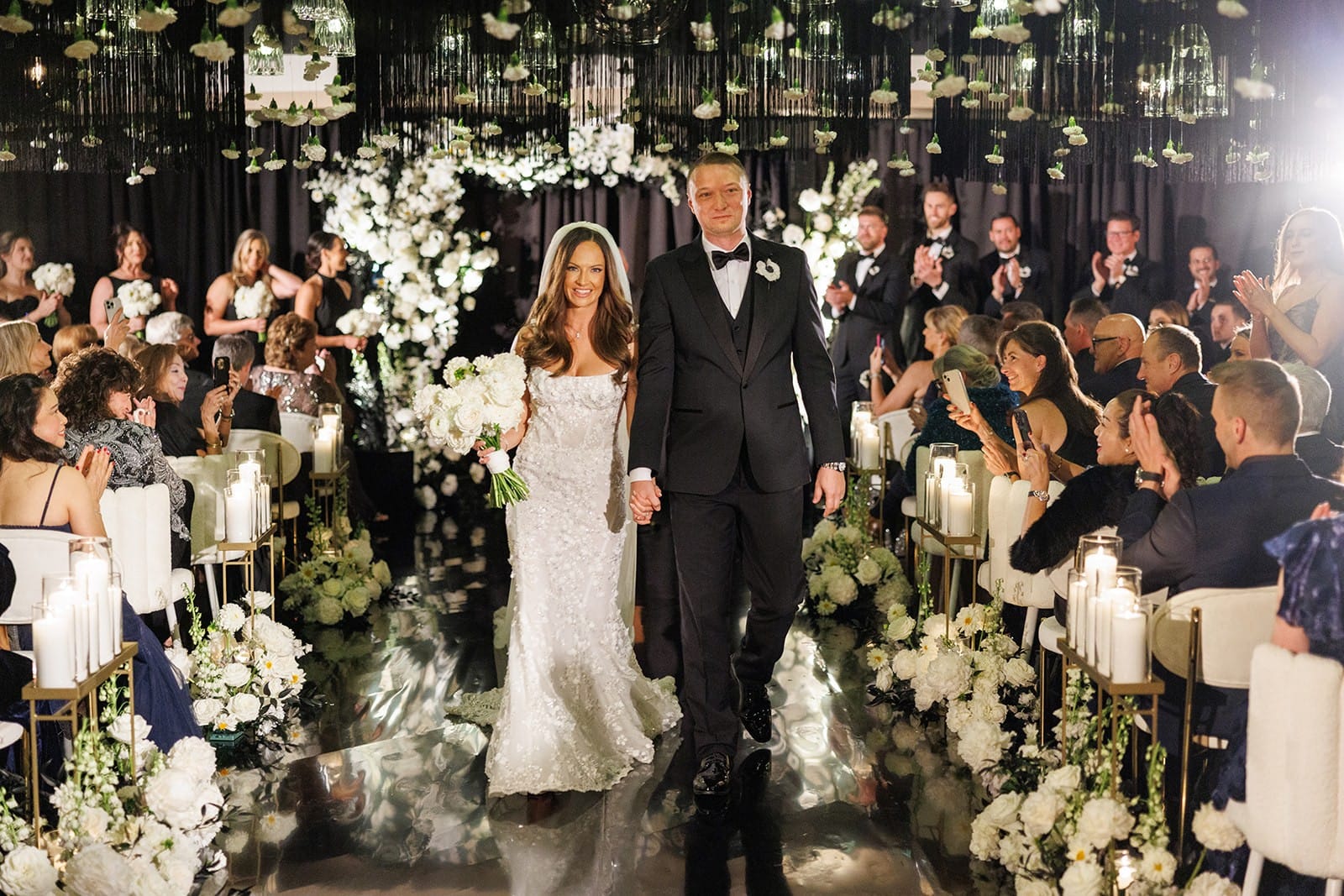 A couple walking back up the aisle through standing guests