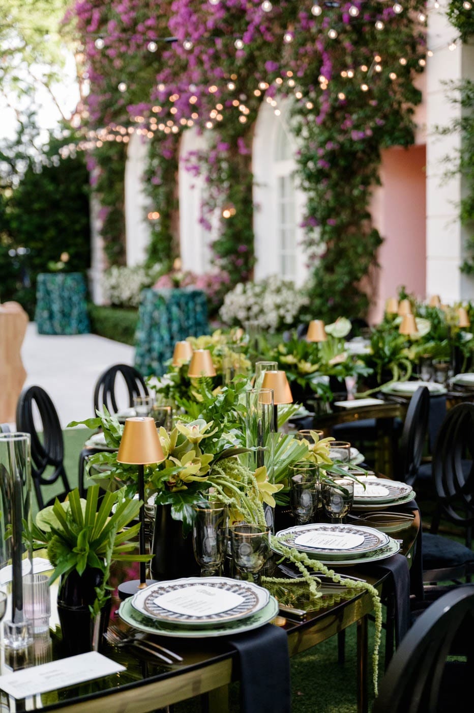 An outdoor table under bougainvillea with green glassware