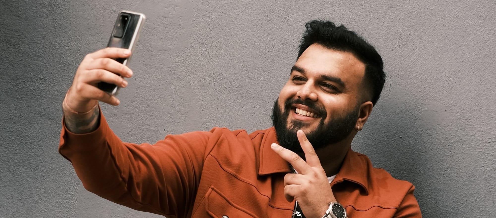woman in brown coat standing beside red wall