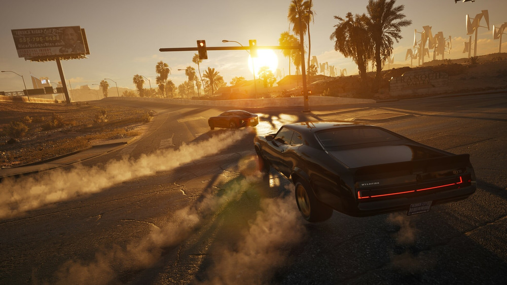 A muscle car drifting around a corner, chasing another car as the sun sets behind plam trees.
