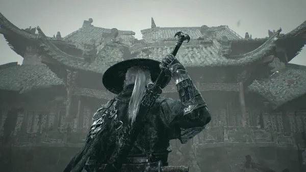 Someone in dark clothing with silver hair grabbing a sword sheathed on their back