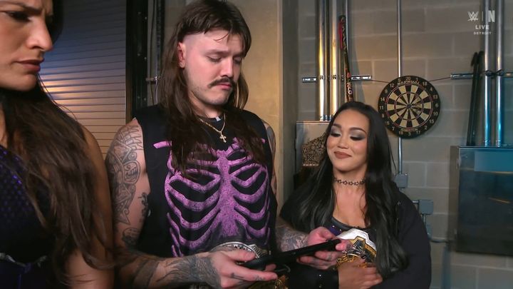 Dominik Mysterio playing a Switch 2 while Roxanne Perez and Raquel Rodriguez watch on