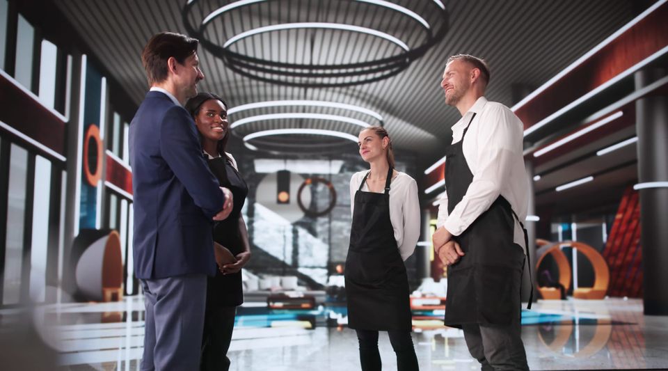 A group of young business professionals meeting with a hotel catering team in a modern conference space, reviewing event plans and food options.
