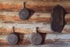 Cast iron pans hanging on the interior wall of a wood log cabin. 