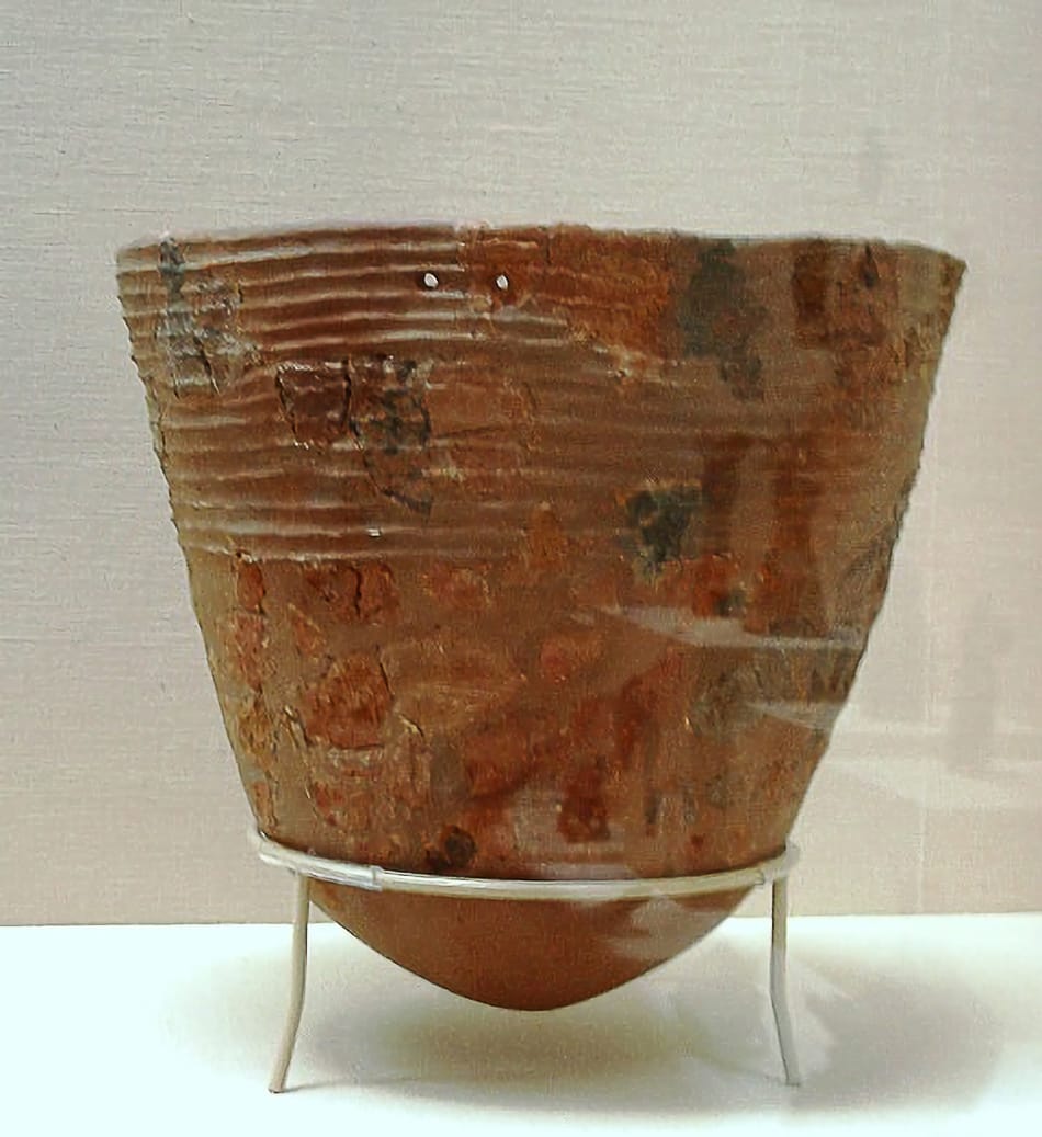 Ancient pottery vessel on a stand on a table