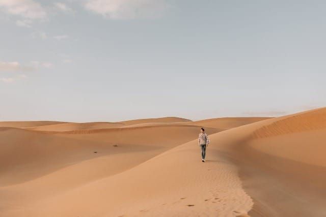 Photo of a man walking in a desert