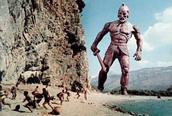Image of a giant bronze man looking at people on a beach
