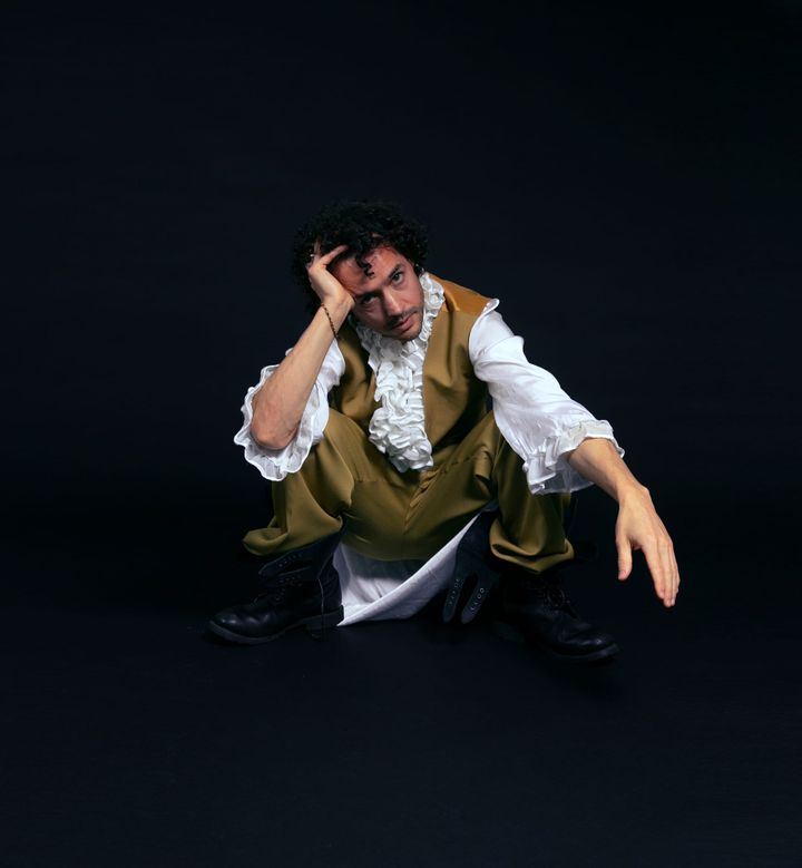 A picture of the artist T. Gowdy crouched against a black backgroun