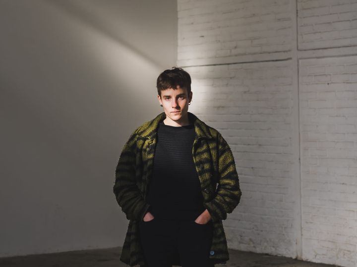 A picture of the artist Nina Garcia, stood wearing a black top with an unzipped green fleece.