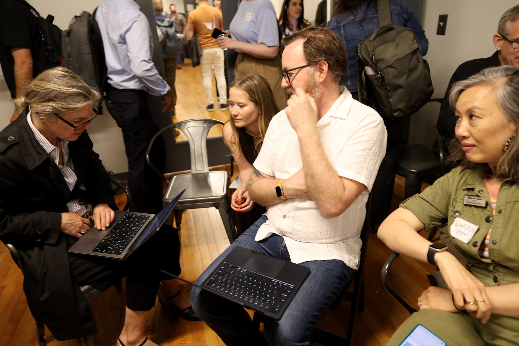 A cluster of summit attendees leaning in around laptops, working together on hands-on AI projects