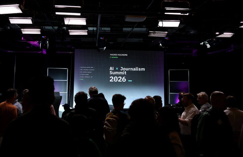 Attendees gather in silhouette before a screen showing the Hacks/Hackers AI × Journalism Summit 2026 title slide.