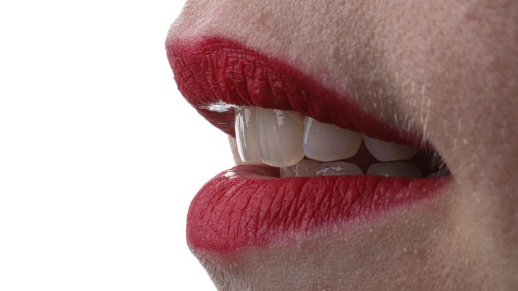 Detailaufnahme eines lächelnden Mundes mit roten Lippen und gut ausgeleuchteten Zähnen – Beispiel für Bildschärfe in der Dentalfotografie.