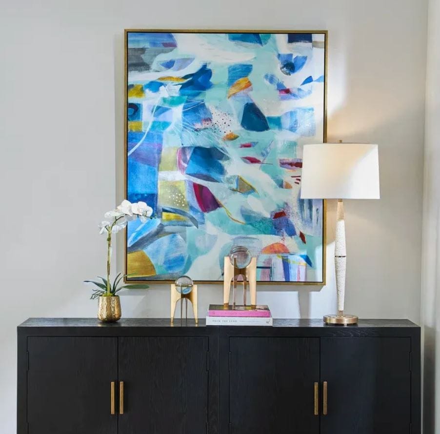 The Story of Water abstract painting by Jill Martin hanging above a black sideboard cabinet