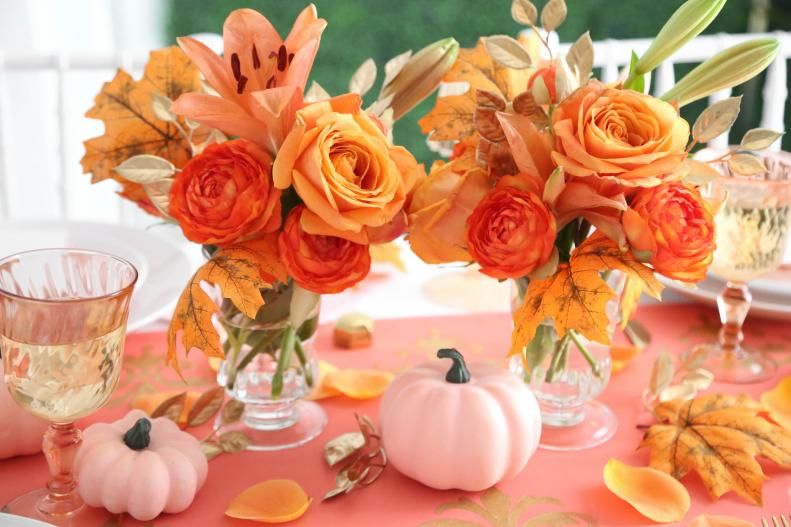 Thanksgiving centerpiece with roses and lilies in cases, pumpkins, and autumn leaves
