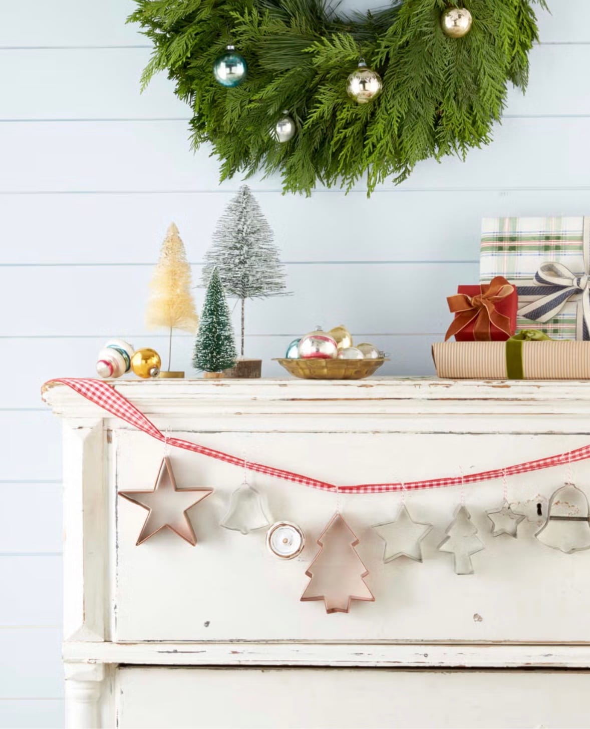 Handmade Christmas garland hanging on a rustic white chest of drawers with simple Christmas decor on top