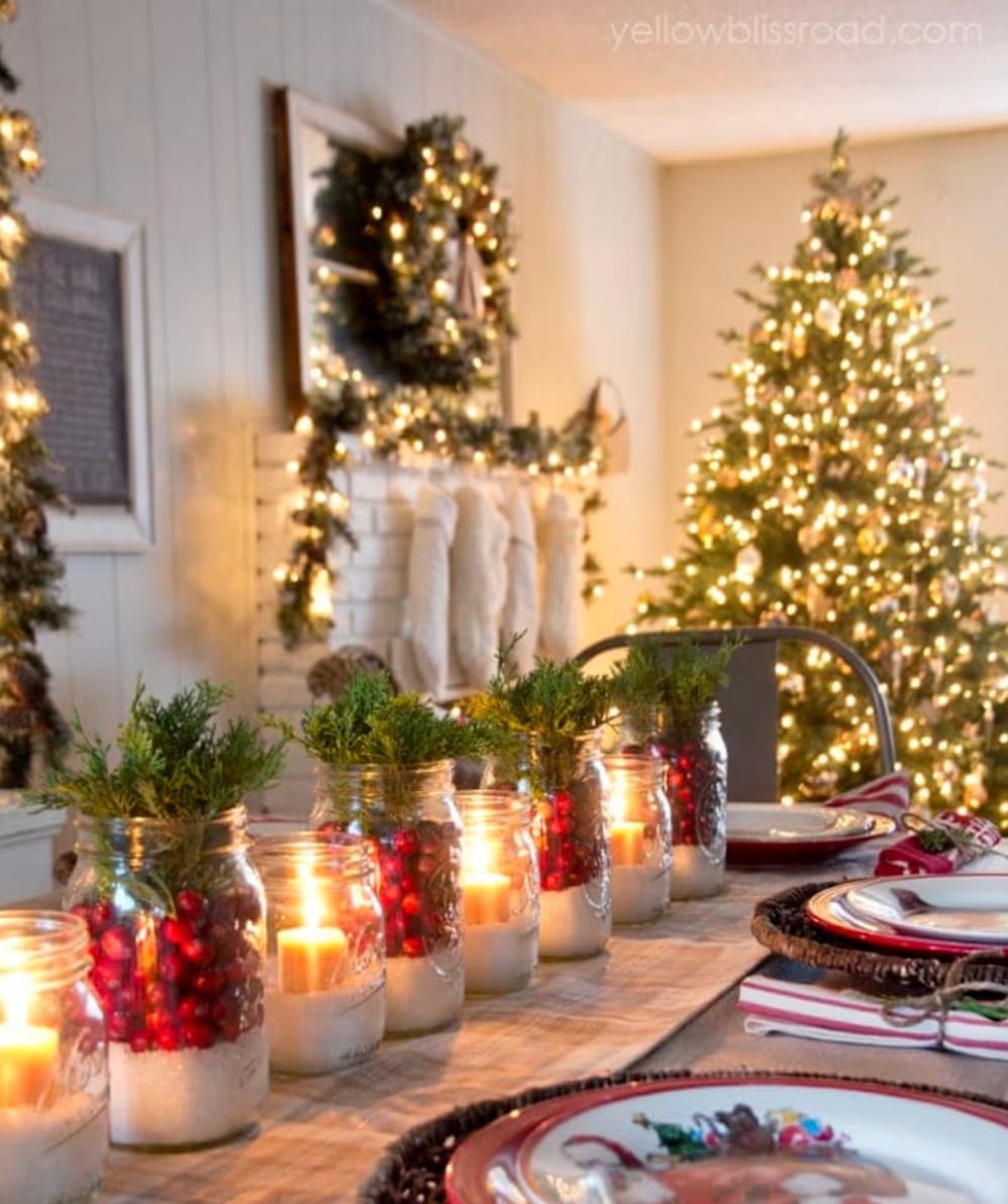 Mason jar centerpieces filled with Epsome salt, votive candles, cranberries, and juniper leaves