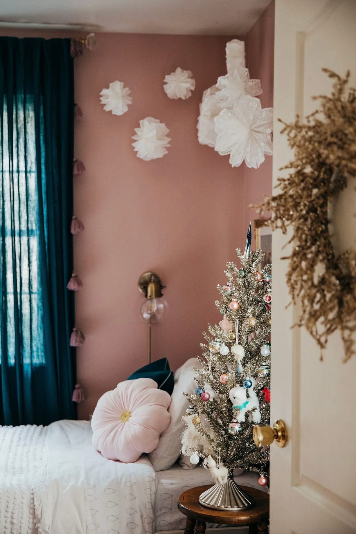 White tissue paper snowflakes hang in the corner against a blush pink wall in a little girl's bedroom