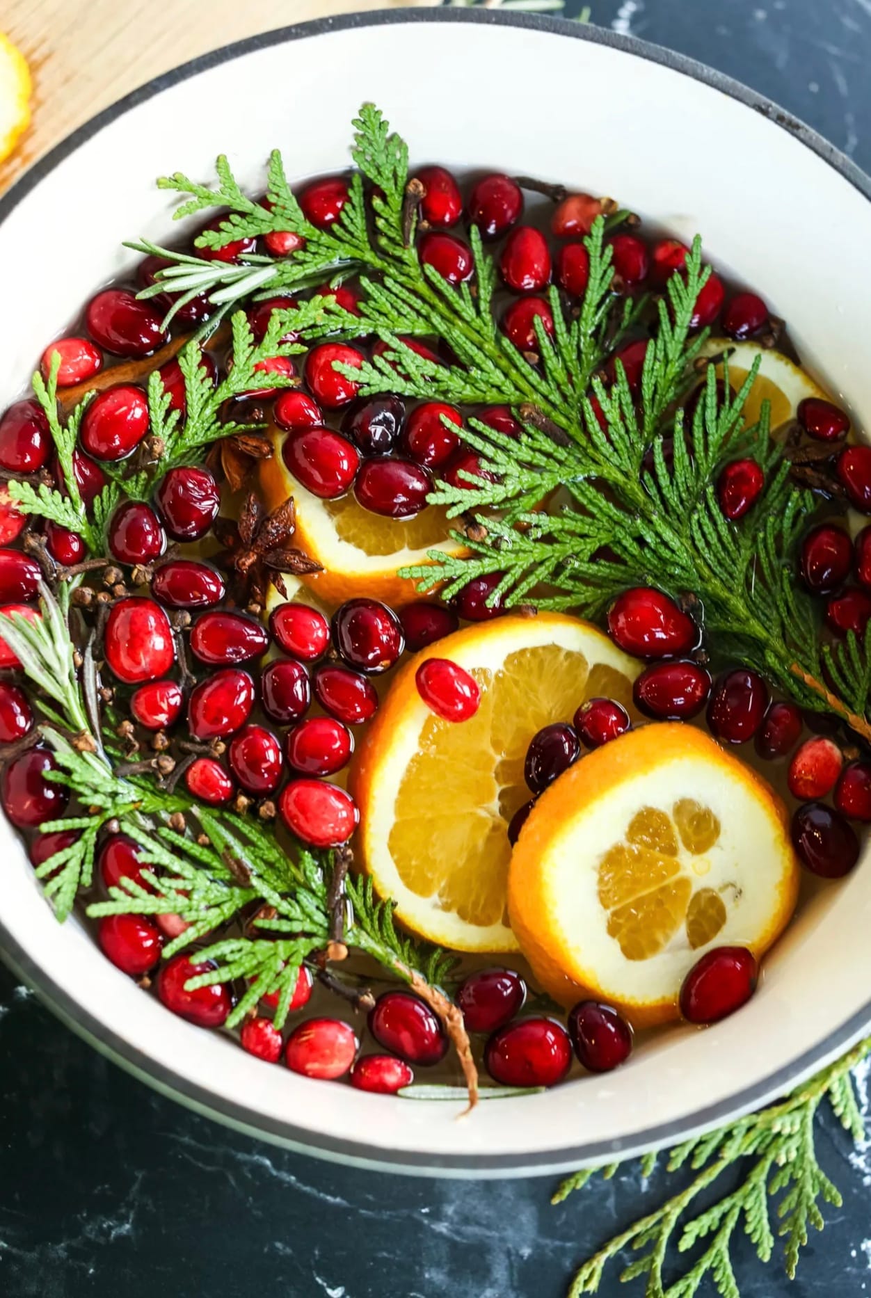 DIY stovetop potpurri made using cranberries, evergreen granches, orange slives, and cloves