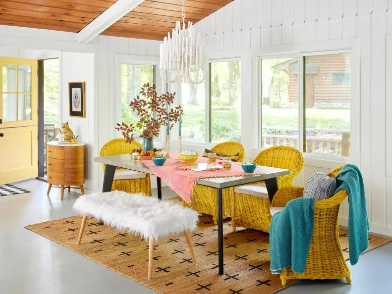 Yellow wicker dining chairs and a fluffy white bench around the dining table