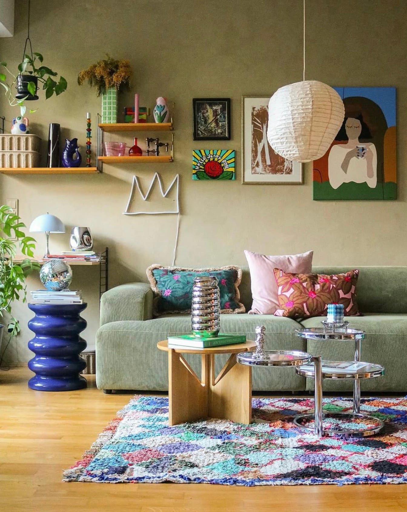 Colorful rug, pillows, artwork, and plants adorn a stylish and artsy living room