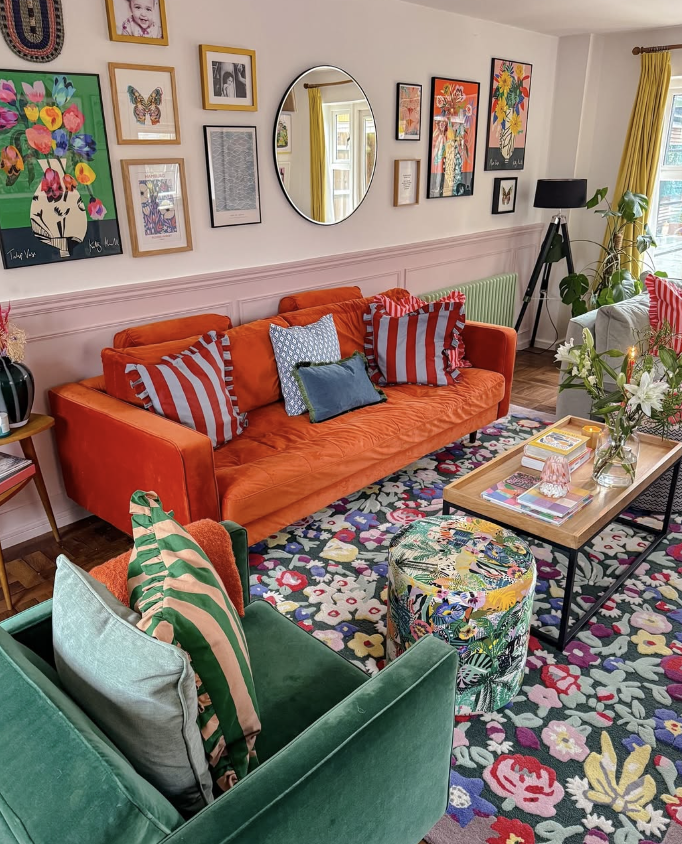 Colorful velvet couches, floral rug, and striped throw pillows are the central patterns in a maximalist living room