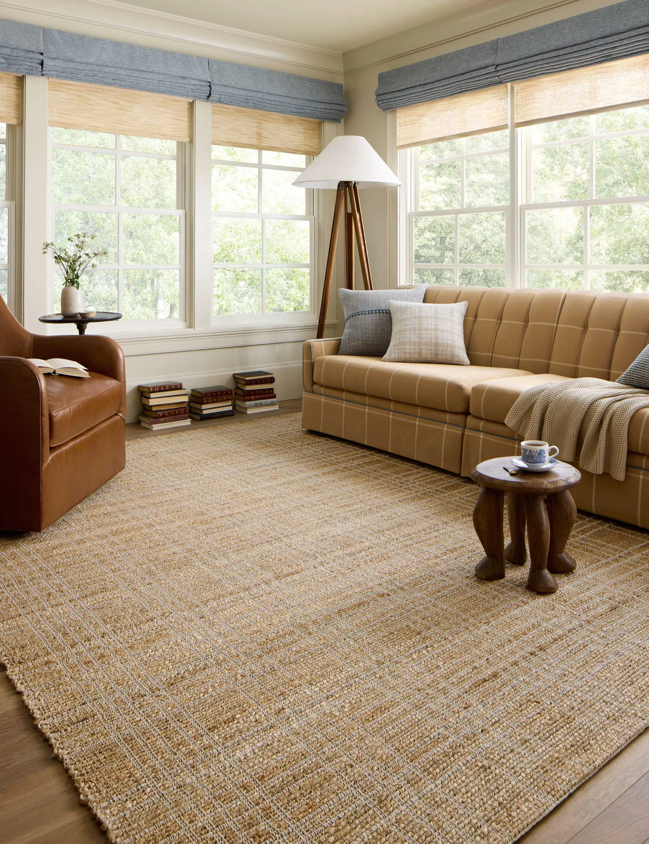 Jute rug in a living room with brown transitional style furniture and airy open windows.