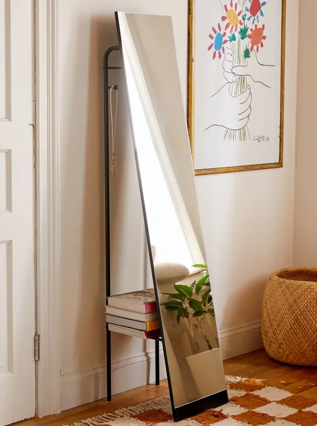 Floor length mirror with book storage leaning against the wall