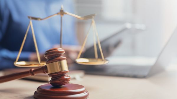 Wooden gavel and scales of justice symbolizing law, fairness, and legal judgment in a courtroom or law office.