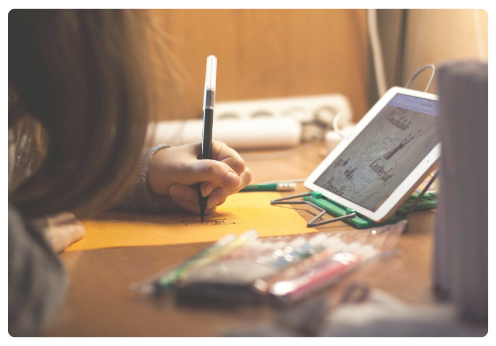 Child drawing with a stylus on a digital tablet next to a notebook and pencil case, illustrating creative, hands-on screen time.         Ask ChatGPT