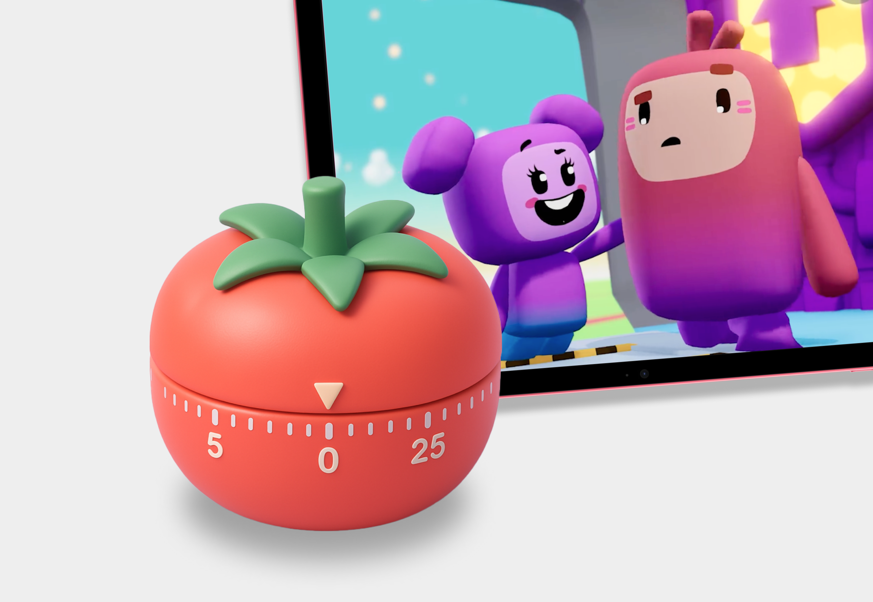 A tomato-shaped kitchen timer sits in front of a screen displaying two animated characters from a kids' game or show.