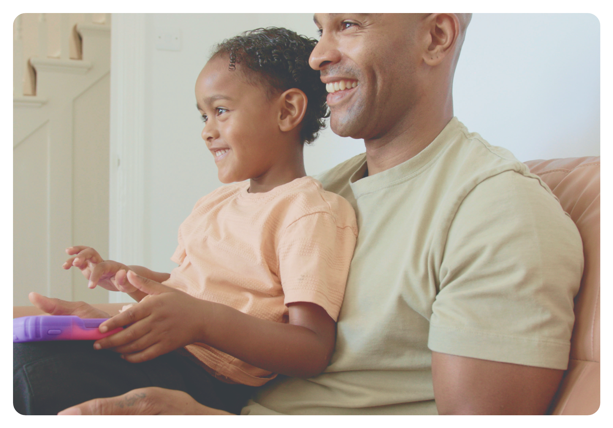 Parent and child smiling while playing together on a tablet using Nurture’s dual-screen feature.