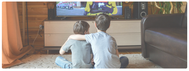Two young kids sitting on the floor watching TV together, representing typical screen time for children ages 4 to 7 and the need to balance quality with quantity.