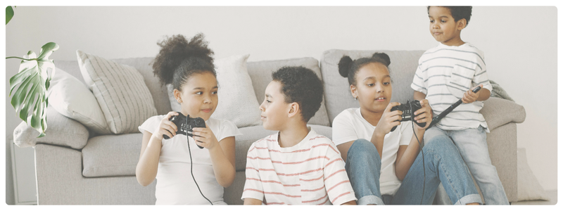 Four kids sitting on a couch playing video games together, highlighting the popularity of gaming in early childhood and the importance of age-appropriate screen use.