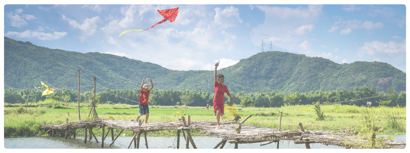 Kids running across a wooden bridge flying kites in a wide open field, representing off-screen exploration and balanced life skills development.