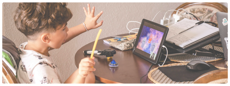 A kid using a tablet and stylus at a computer desk, illustrating how digital games can support problem-solving and critical thinking skills.