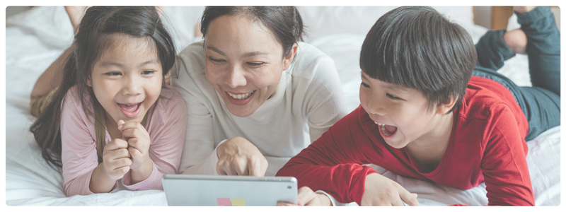Two kids and an adult smiling and watching a tablet together, modeling screen-based empathy and social connection through shared digital experiences.