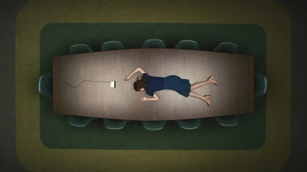 A woman in blue skirt and sweater lies, apparently asleep, on a conference room table. An intercom rests at her head. The chairs around the table a very neatly aligned and completely empty.