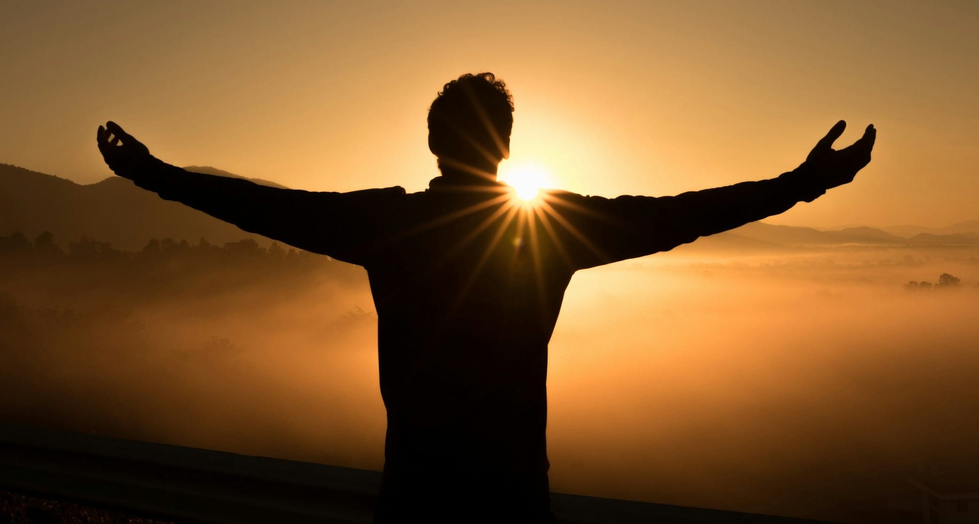 silhouette photo of man on cliff during sunset