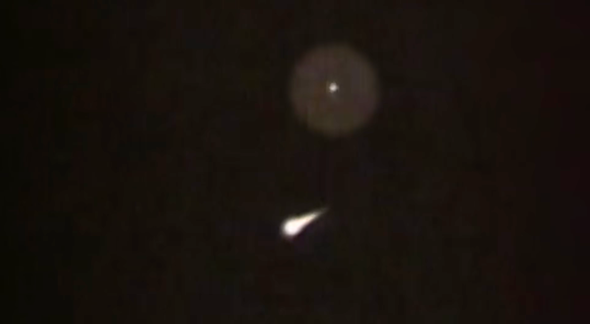 A bright point of light circled in the upper frame, with the re-entry vehicle streaking below it against a black sky.