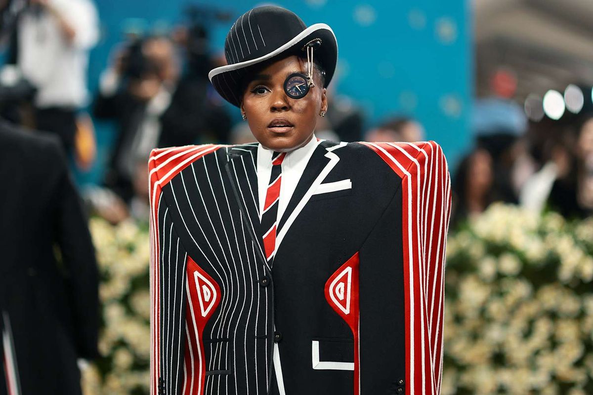 Image of Janelle Monaé at the 2025 Met Gala. They are a Black person wearing an exaggerated pinstripe suit with large, squared shoulder pads. They are also wearing a bowler hat and a monocle