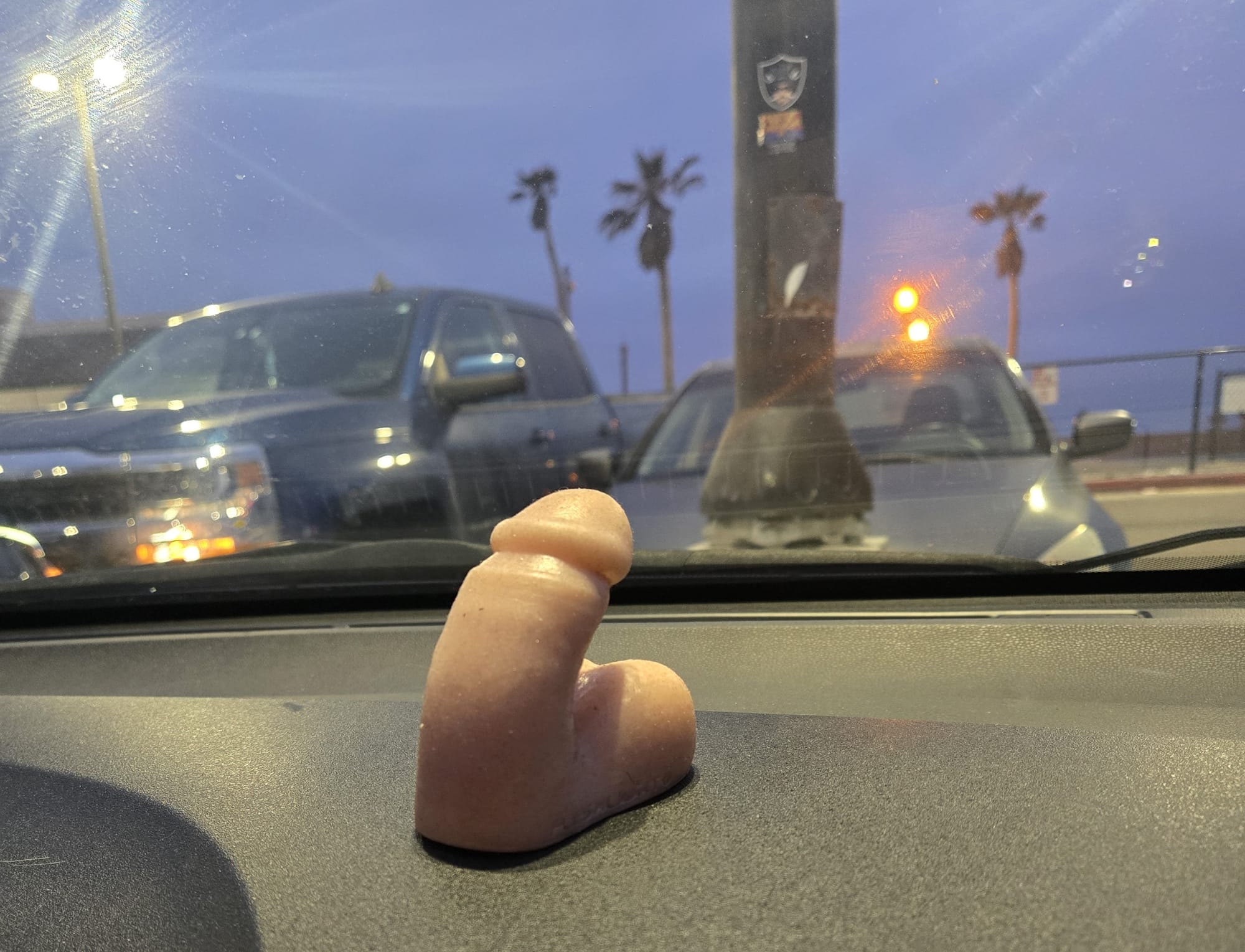 A small Mr. Limpy sits proud on a gray car dashboard