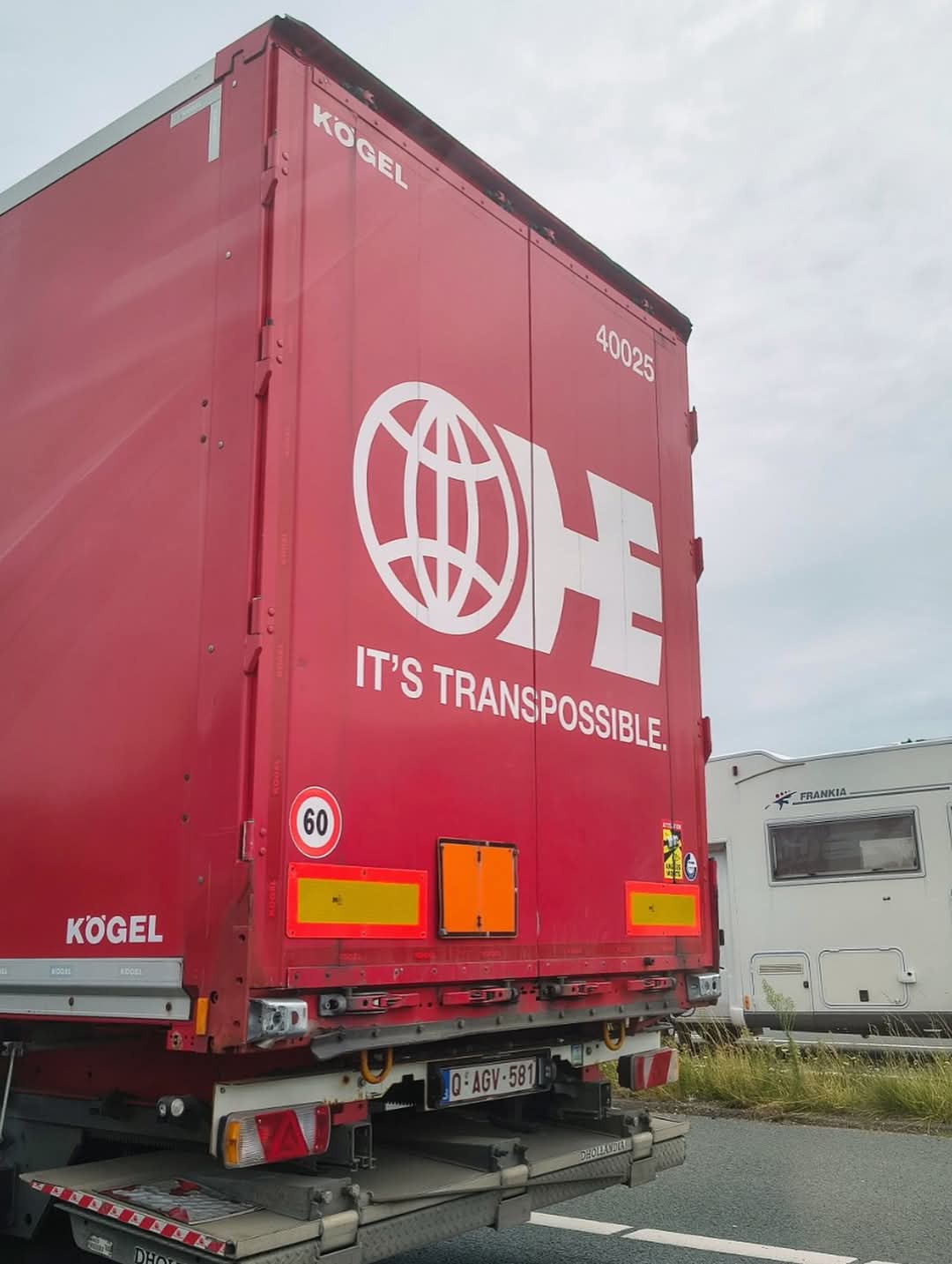 The back of a red semitruck with a white logo that reads It's Transpossible.