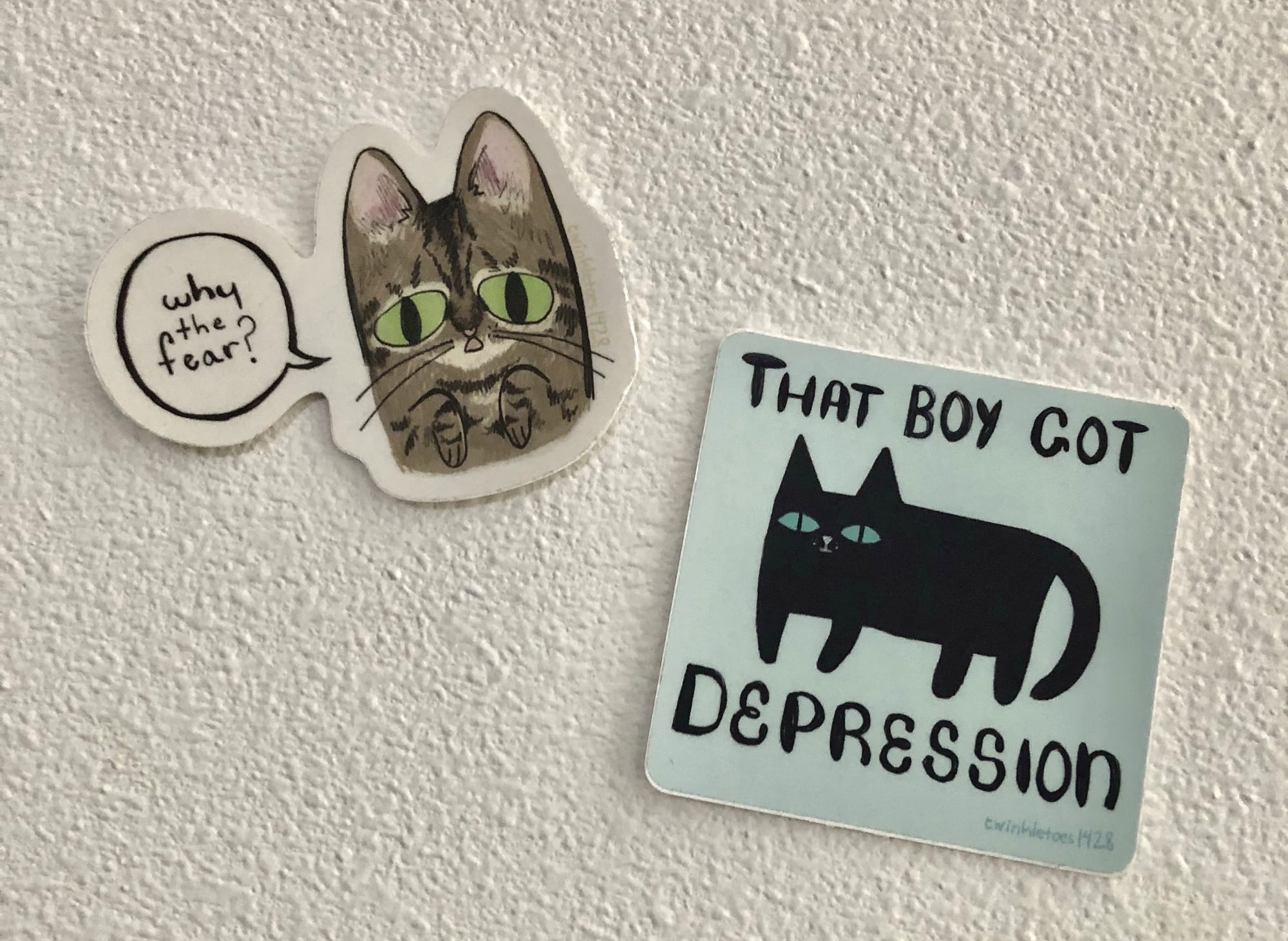 two stickers by tulani kiara--one of a brown tabby cat saying why the fear? and another with a black cat and the words that boy got depression